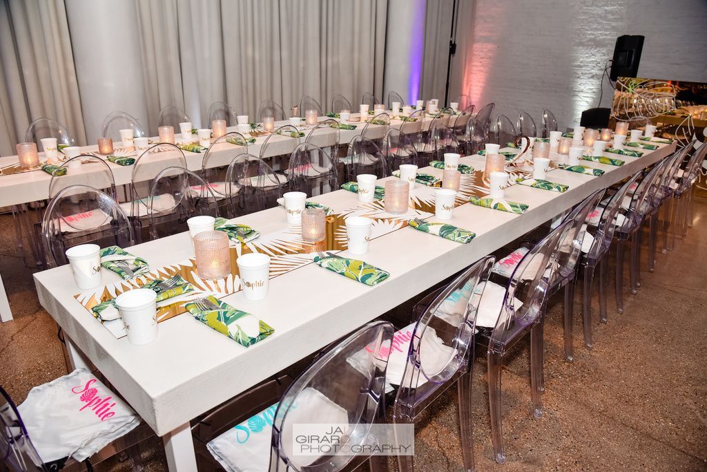 A long table with clear chairs is set up for a party.