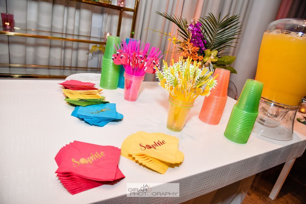 A table with colorful cups , napkins , and flowers on it.