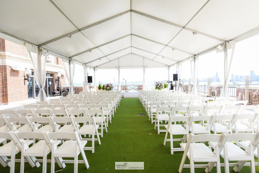 Rows of white folding chairs under a white tent