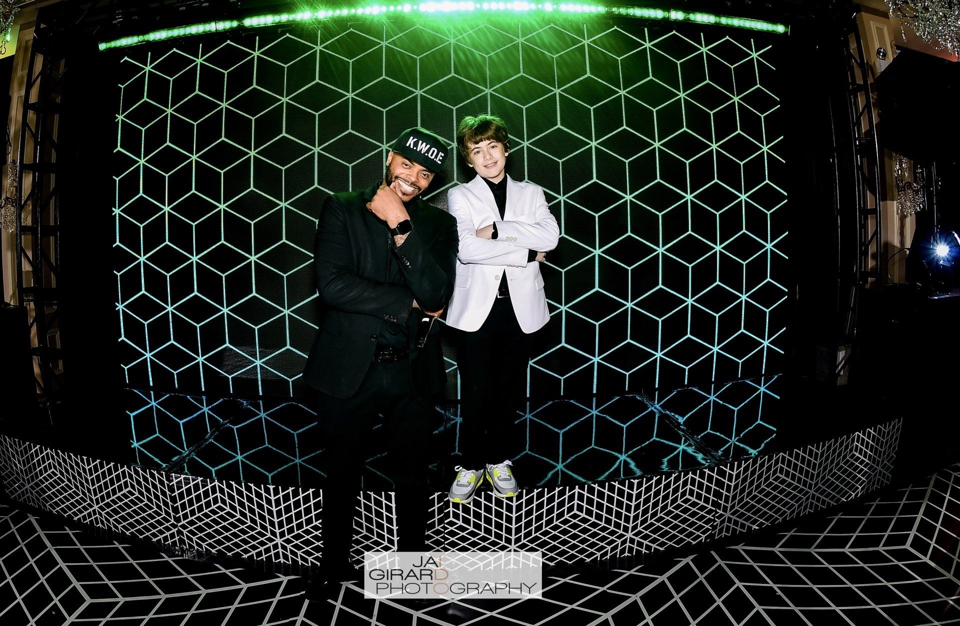 Two men are standing next to each other in front of a green light.