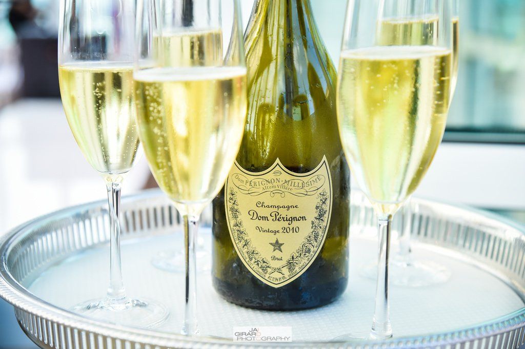 A bottle of champagne and three glasses of champagne on a tray.