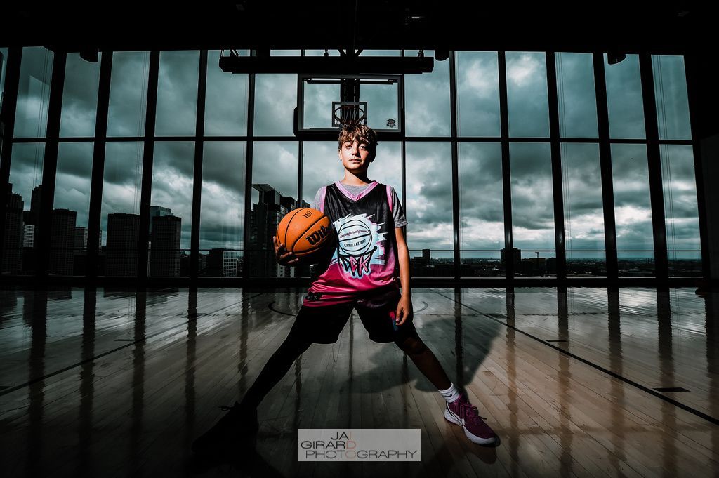 A young boy is holding a basketball in a gym.