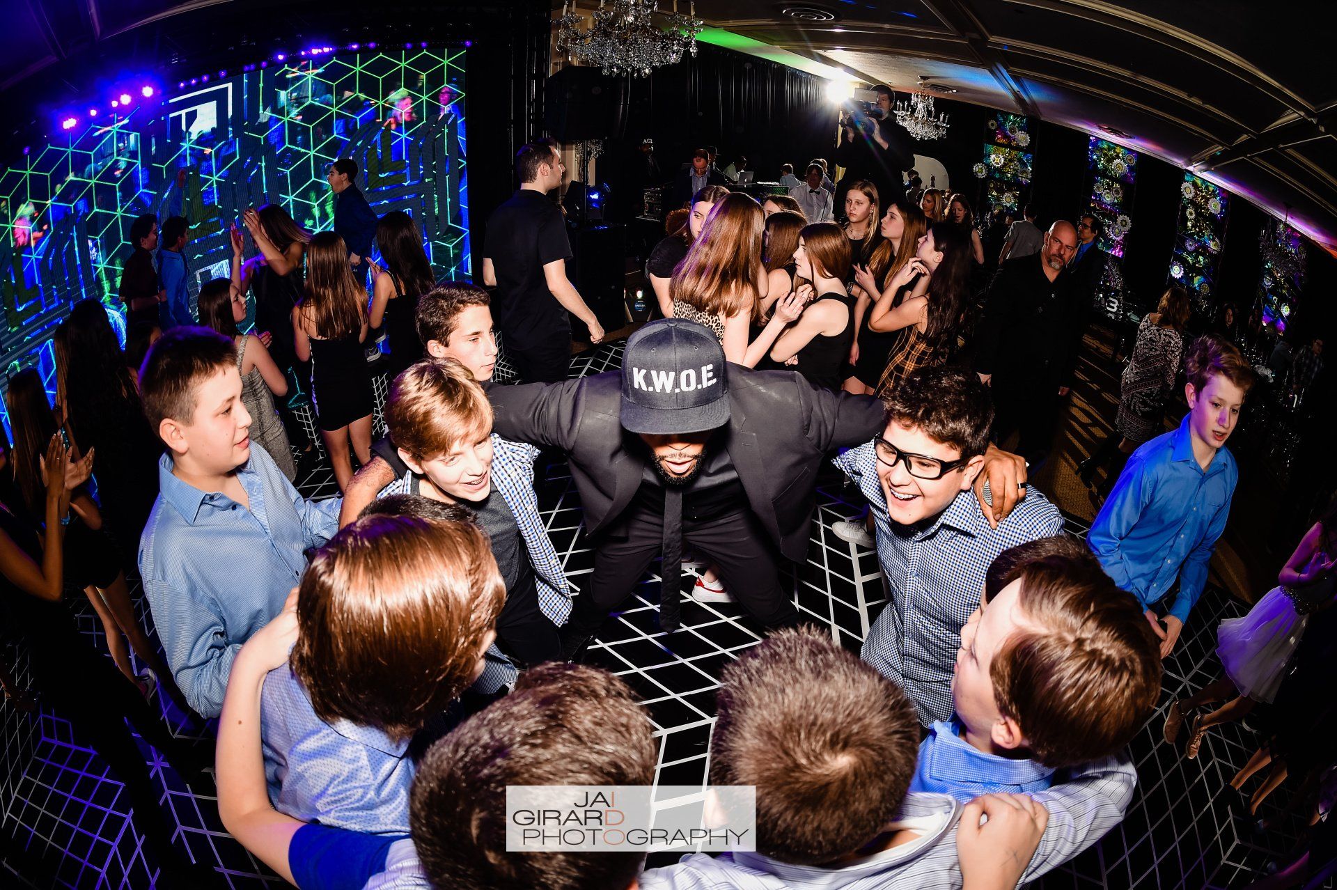 A group of people are dancing in a dark room at a party.