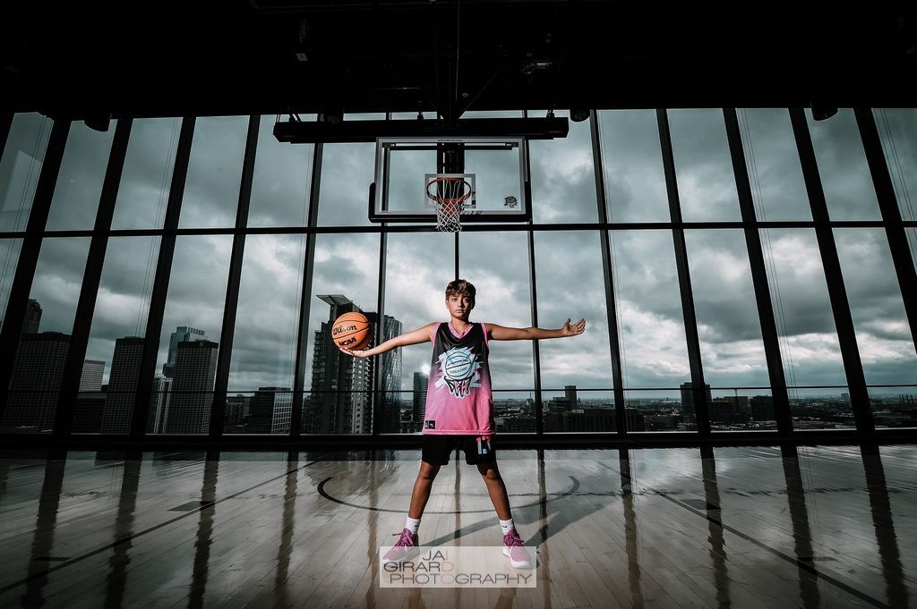 A basketball player is standing in front of a basketball hoop holding a basketball.
