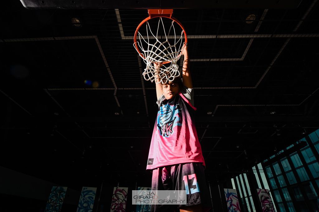 A person is doing a handstand in front of a basketball hoop.