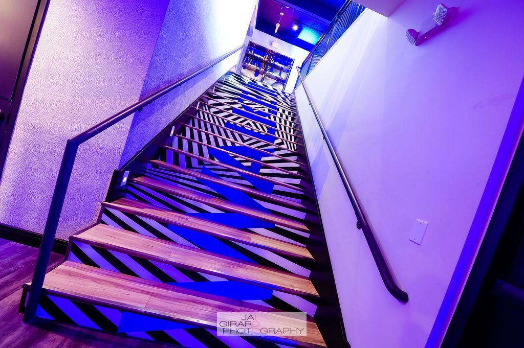 A set of stairs leading up to a room with purple lights.