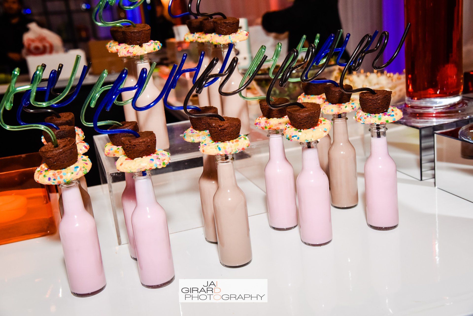 A table topped with bottles of milkshakes and brownies on sticks.