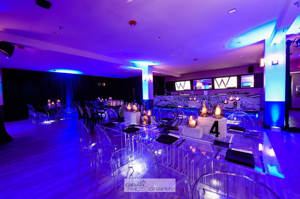 A large room filled with tables and chairs and purple lights.