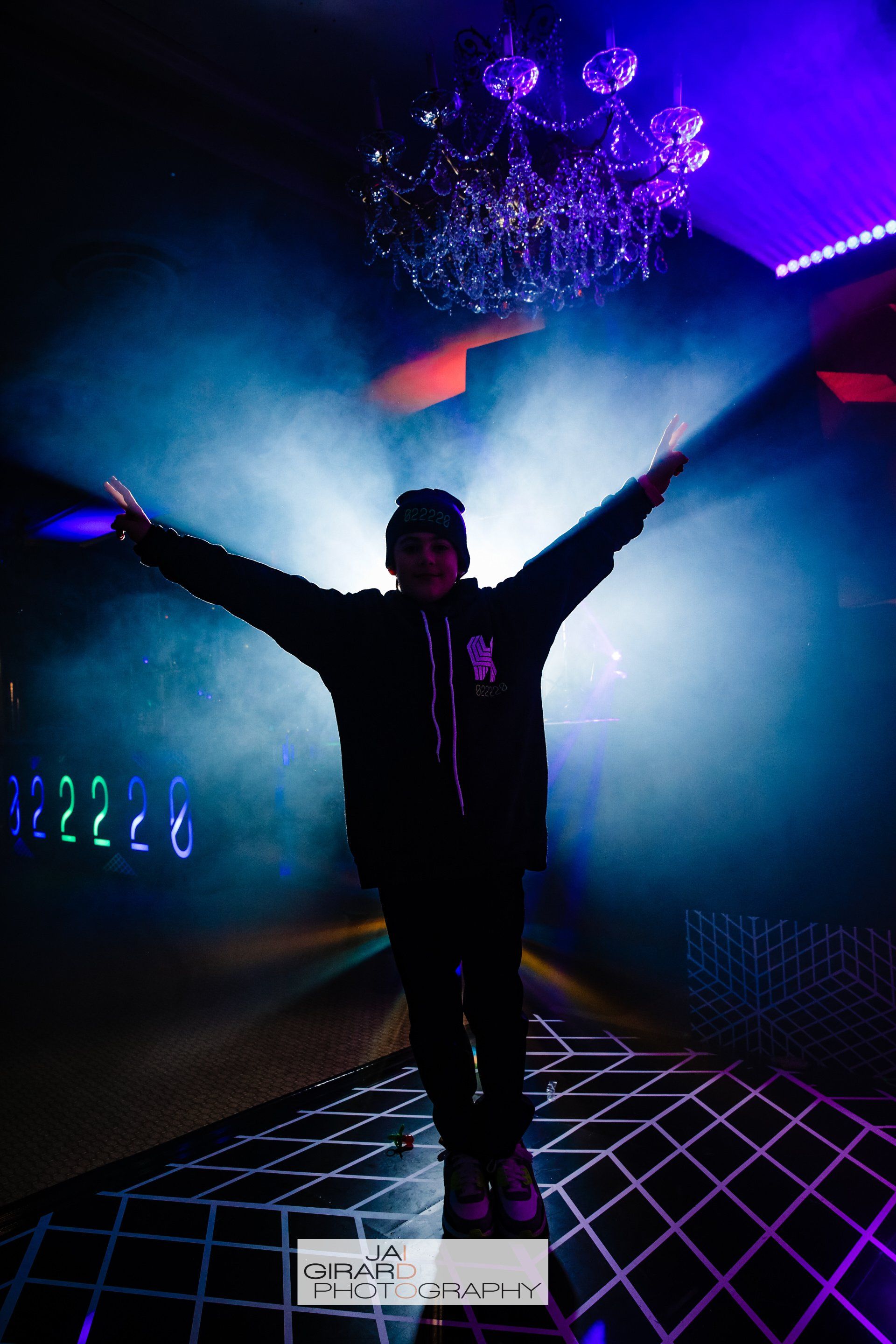 A man is standing in a dark room with his arms outstretched.