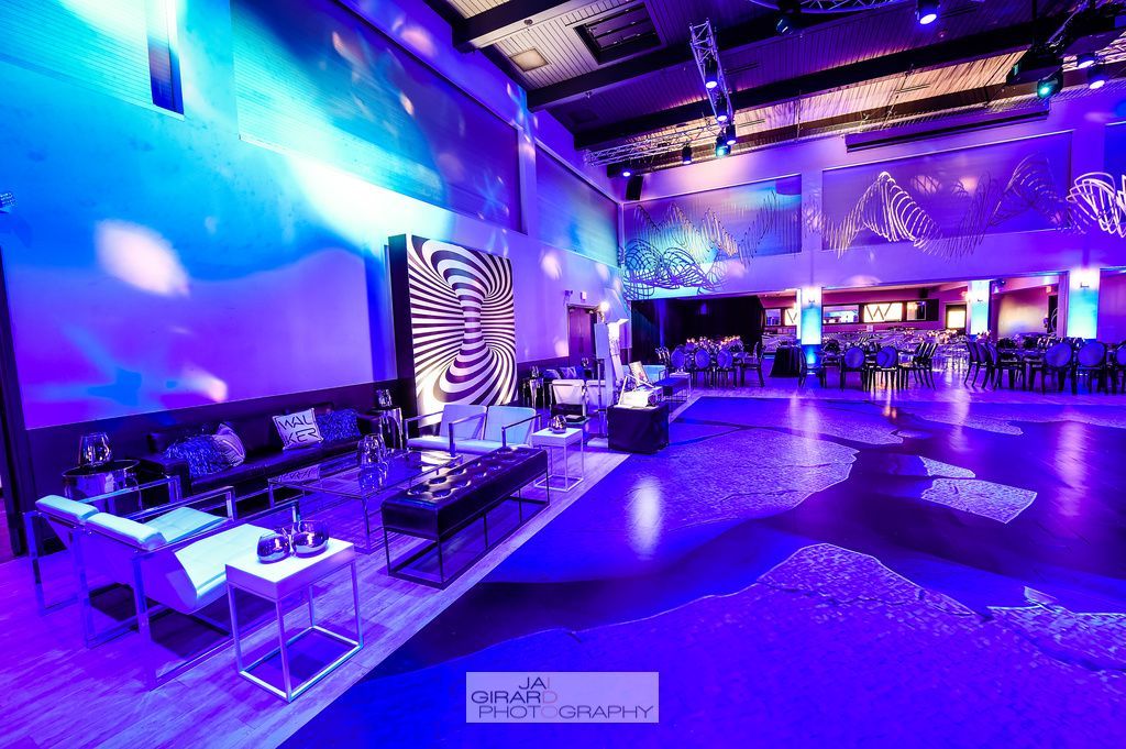 A large room with purple lights on the walls and a dance floor.