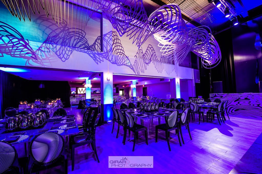 A large room with tables and chairs and purple lights.