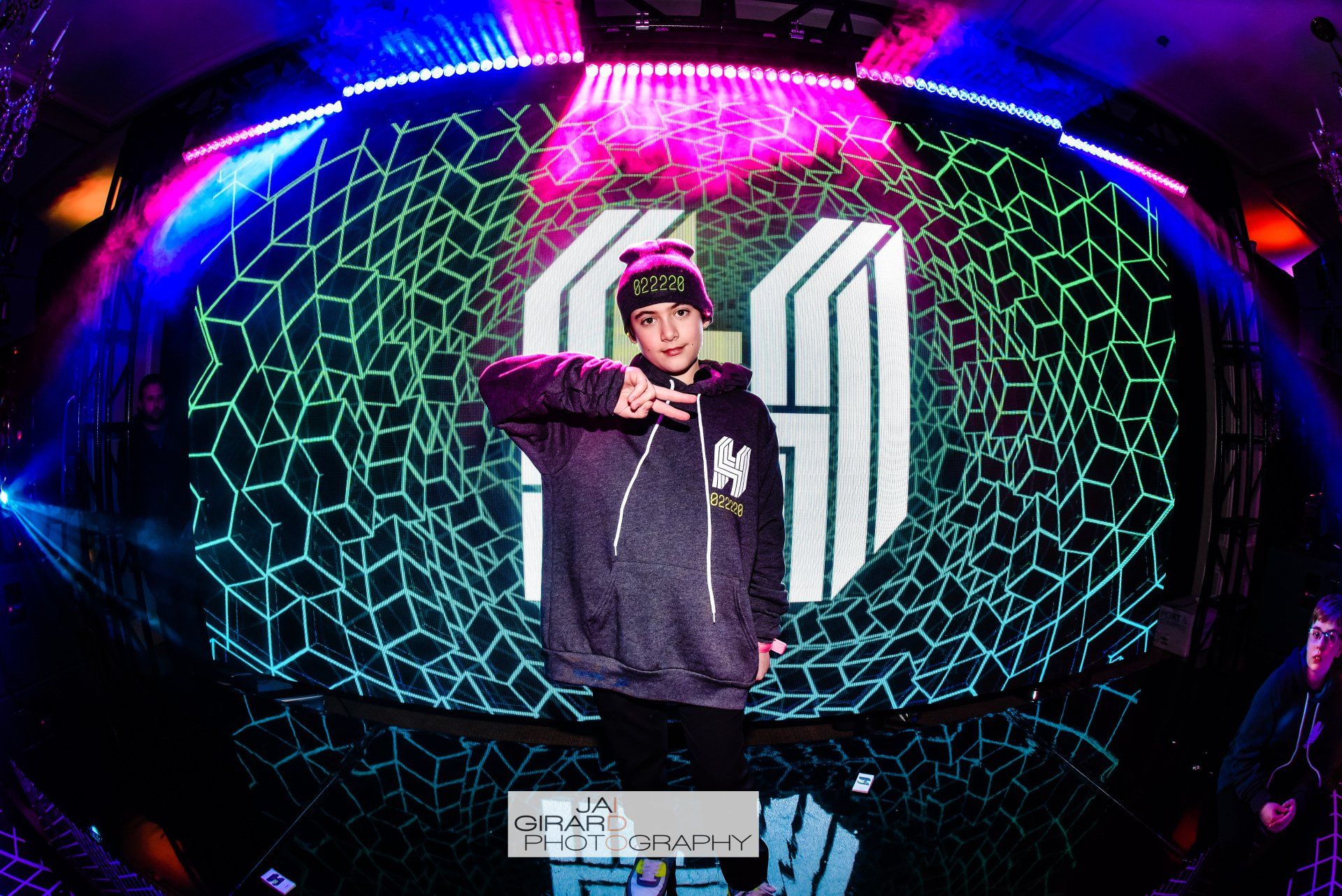 A man is standing in front of a large screen with the letter m on it