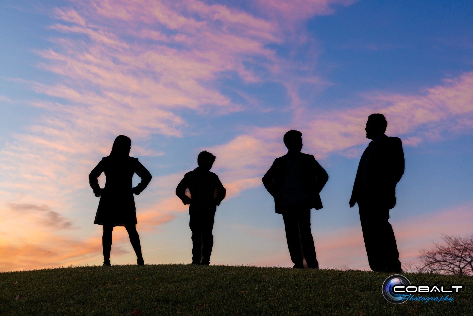 A group of people standing on top of a grass covered hill