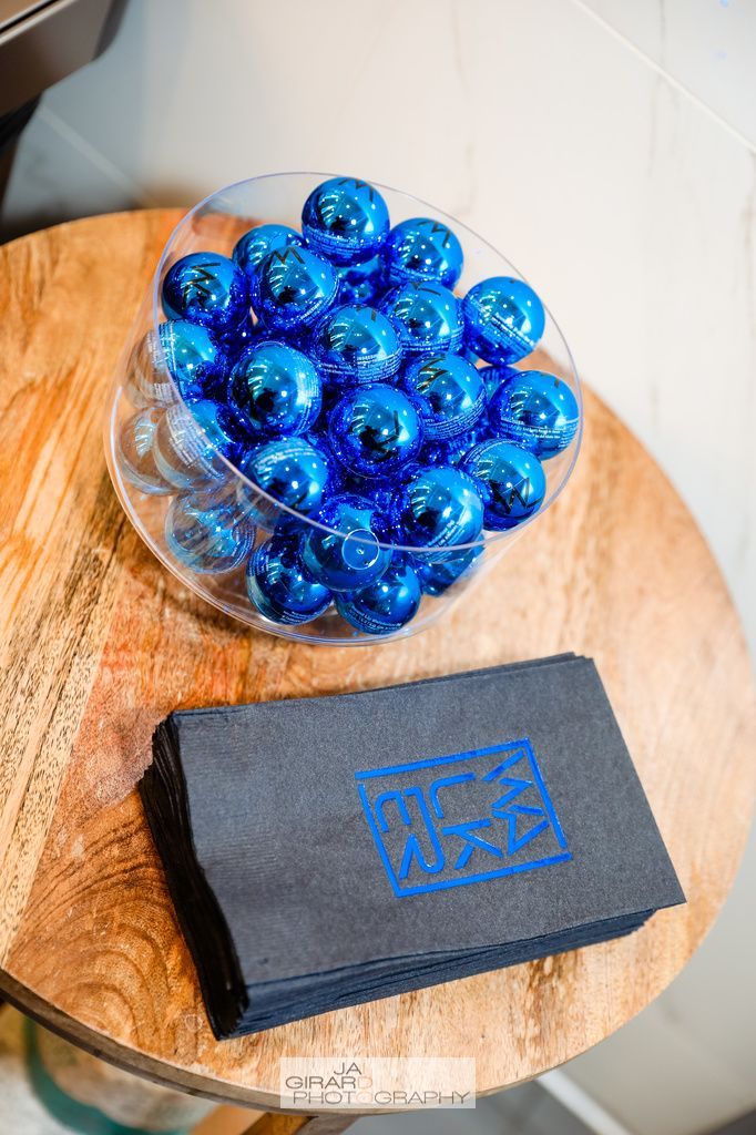 A bowl of blue balls is sitting on a wooden table next to a napkin.