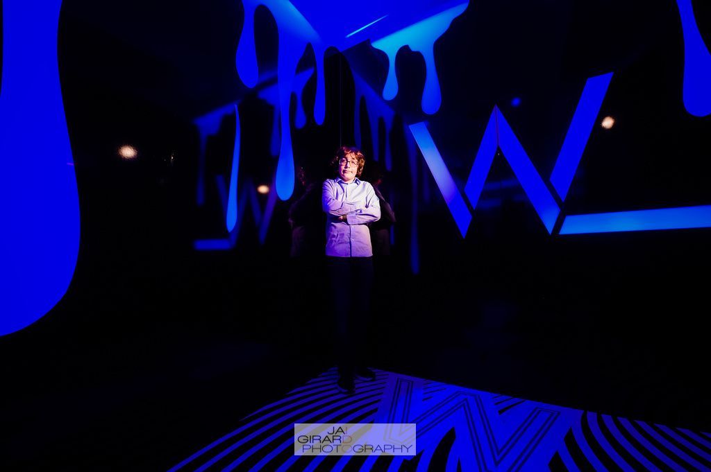 A man is standing in front of a wall with the letter w on it