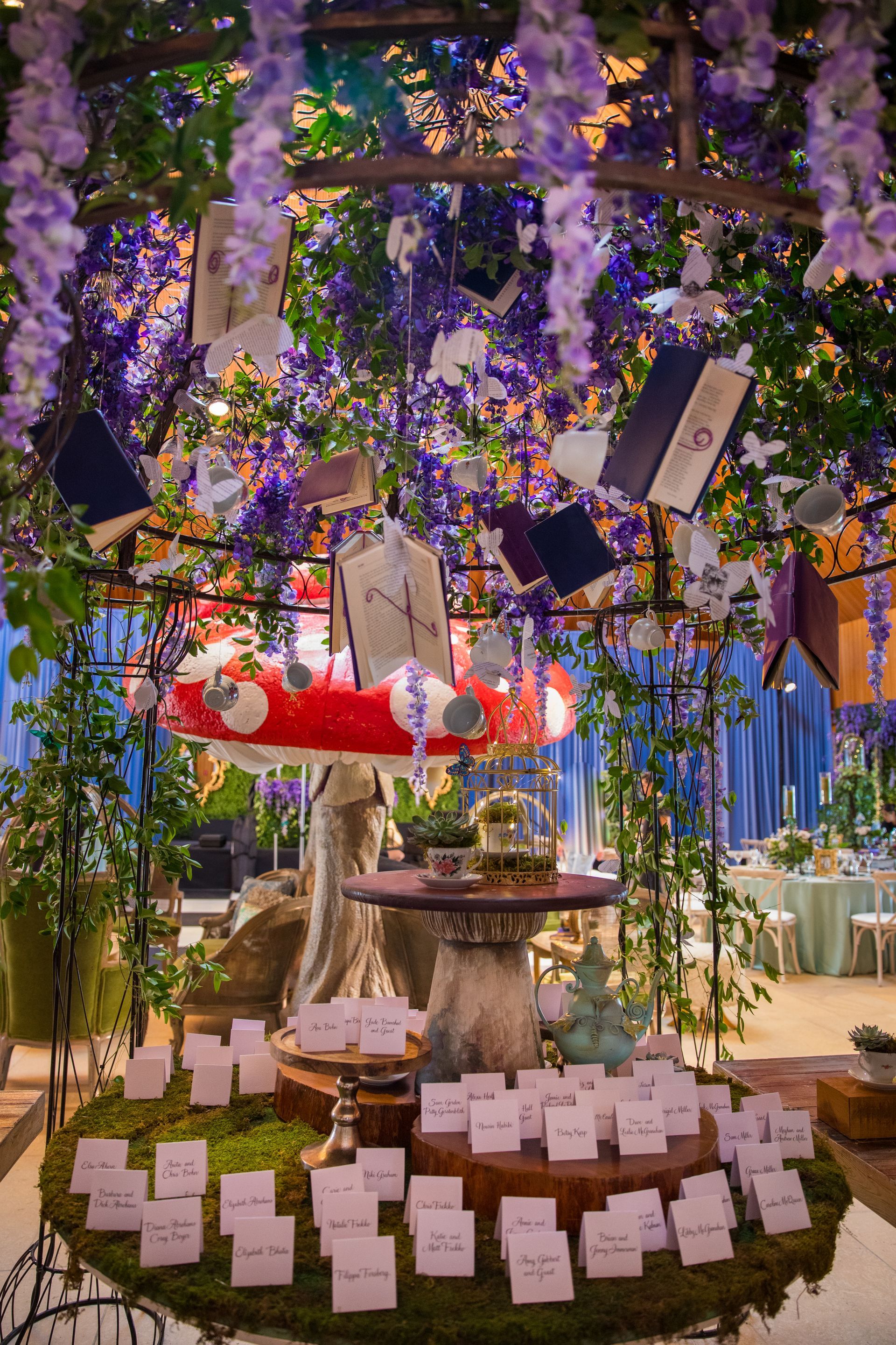 A table with a lot of cards on it and flowers hanging from the ceiling.