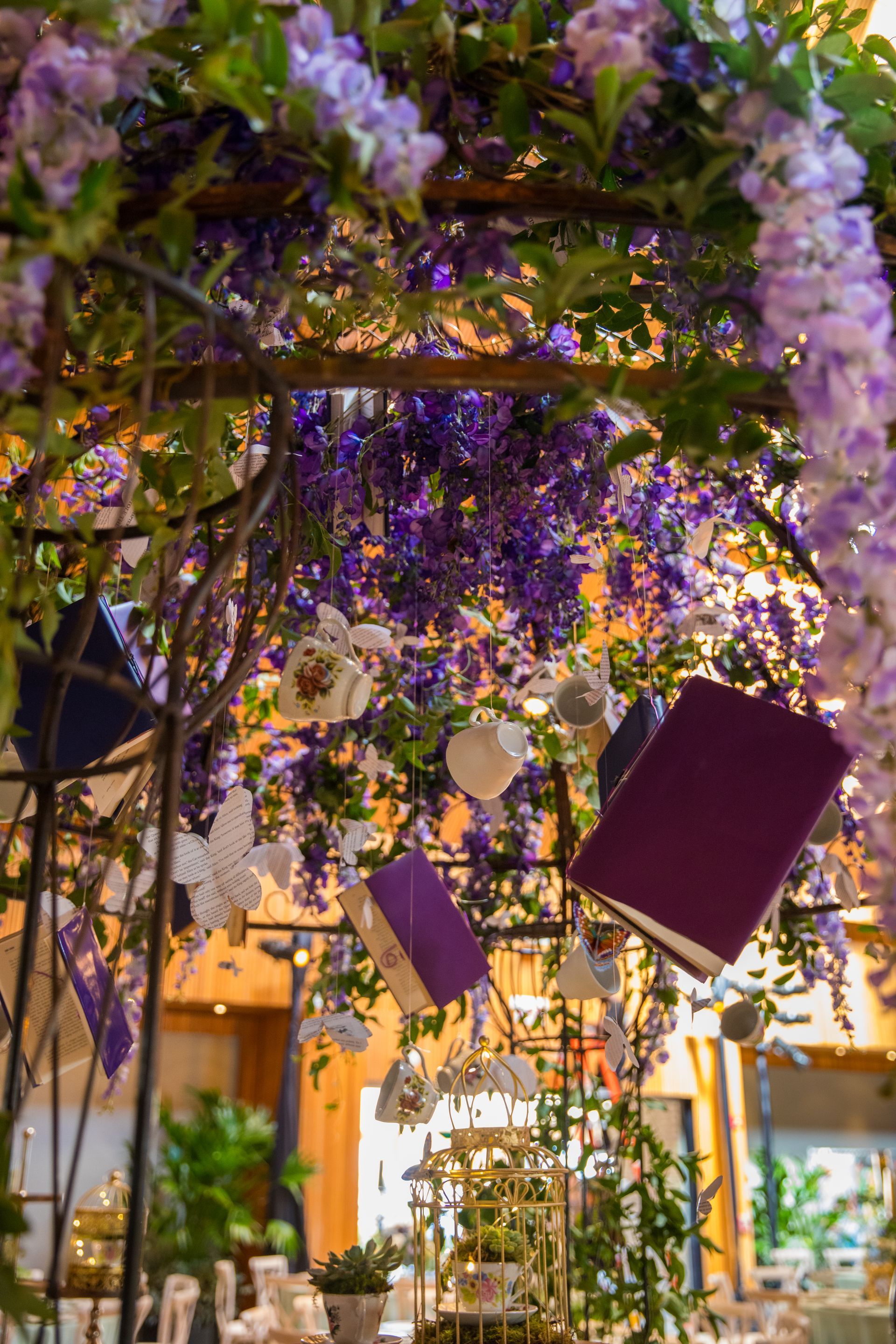 A bunch of books hanging from a tree with purple flowers.