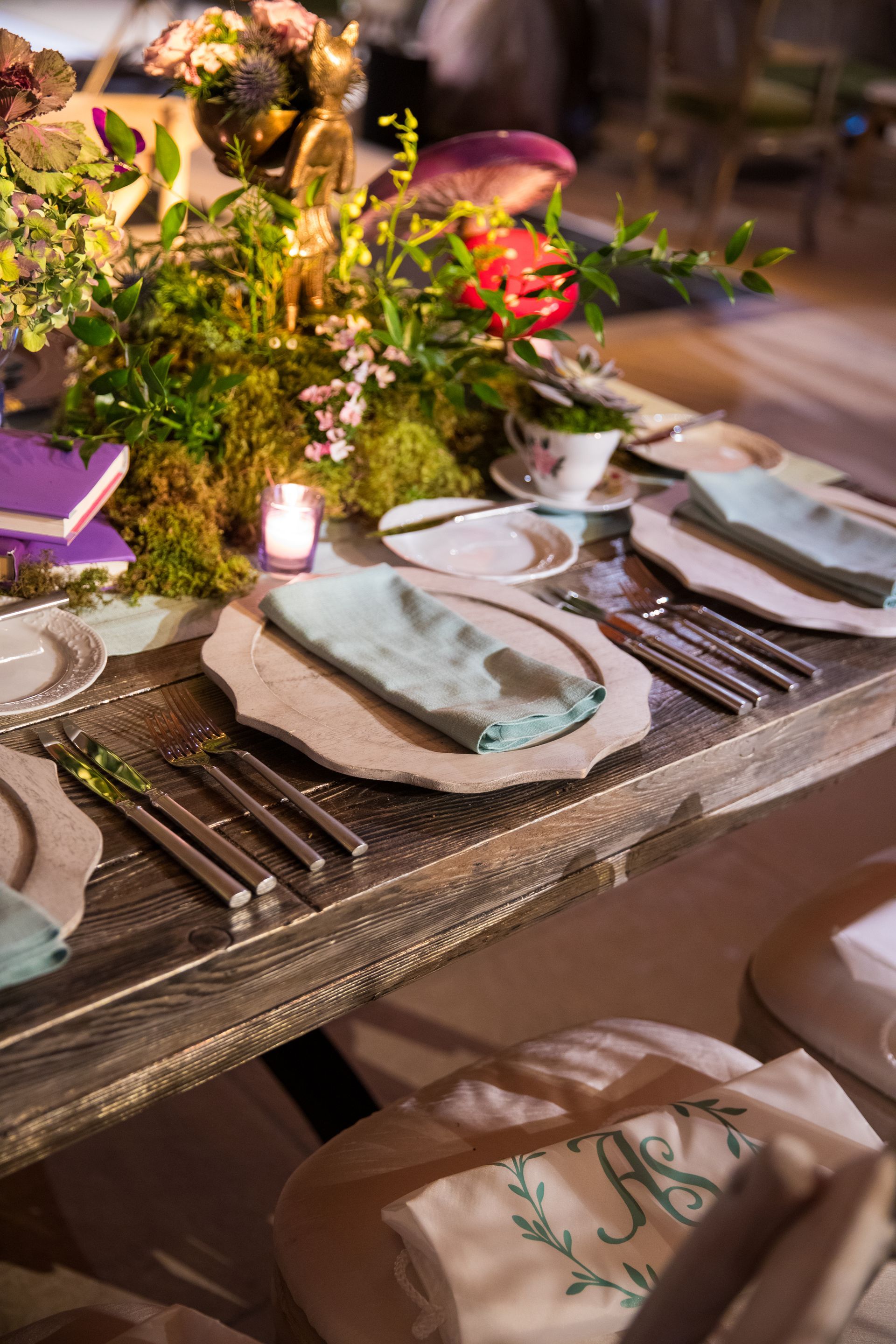 A wooden table with plates , silverware , and flowers on it.