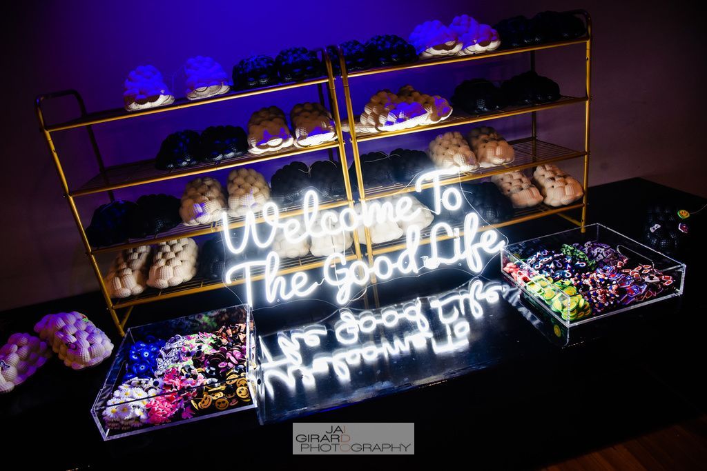 A neon sign that says `` welcome to the good life '' is lit up in a dark room.