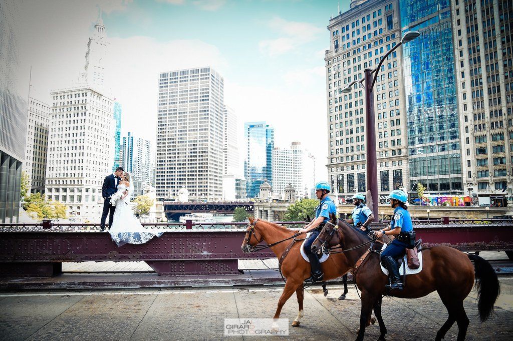 A bride and groom are posing for a picture with two police officers on horseback.