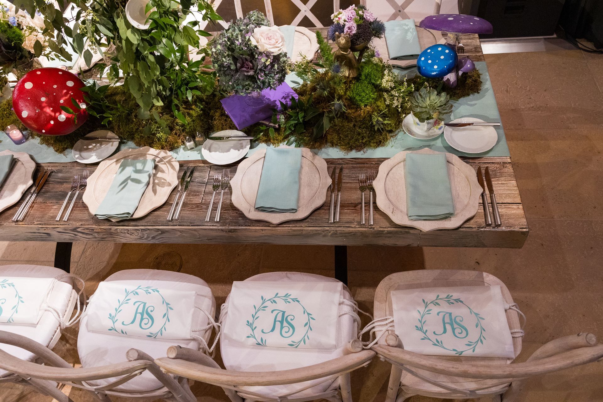 A wooden table with plates , napkins , and silverware on it.