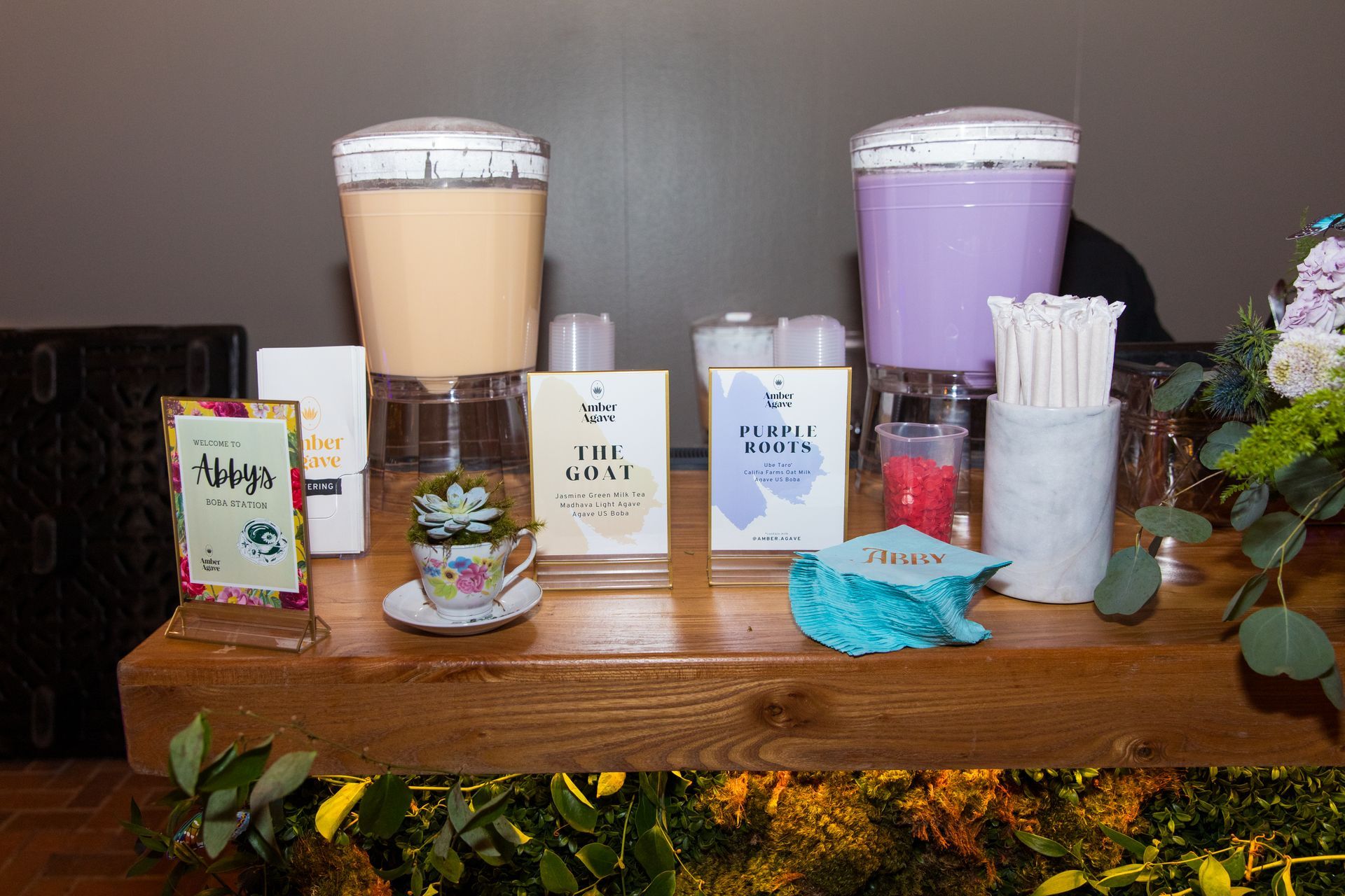 A wooden table topped with a variety of drinks and flowers.