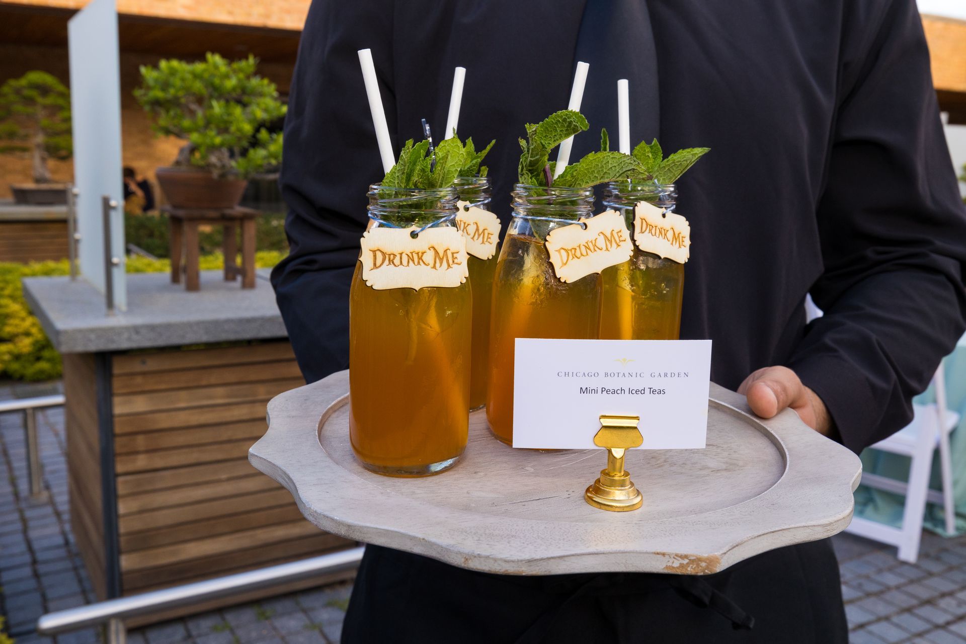 A waiter is holding a tray of drinks with straws on it.