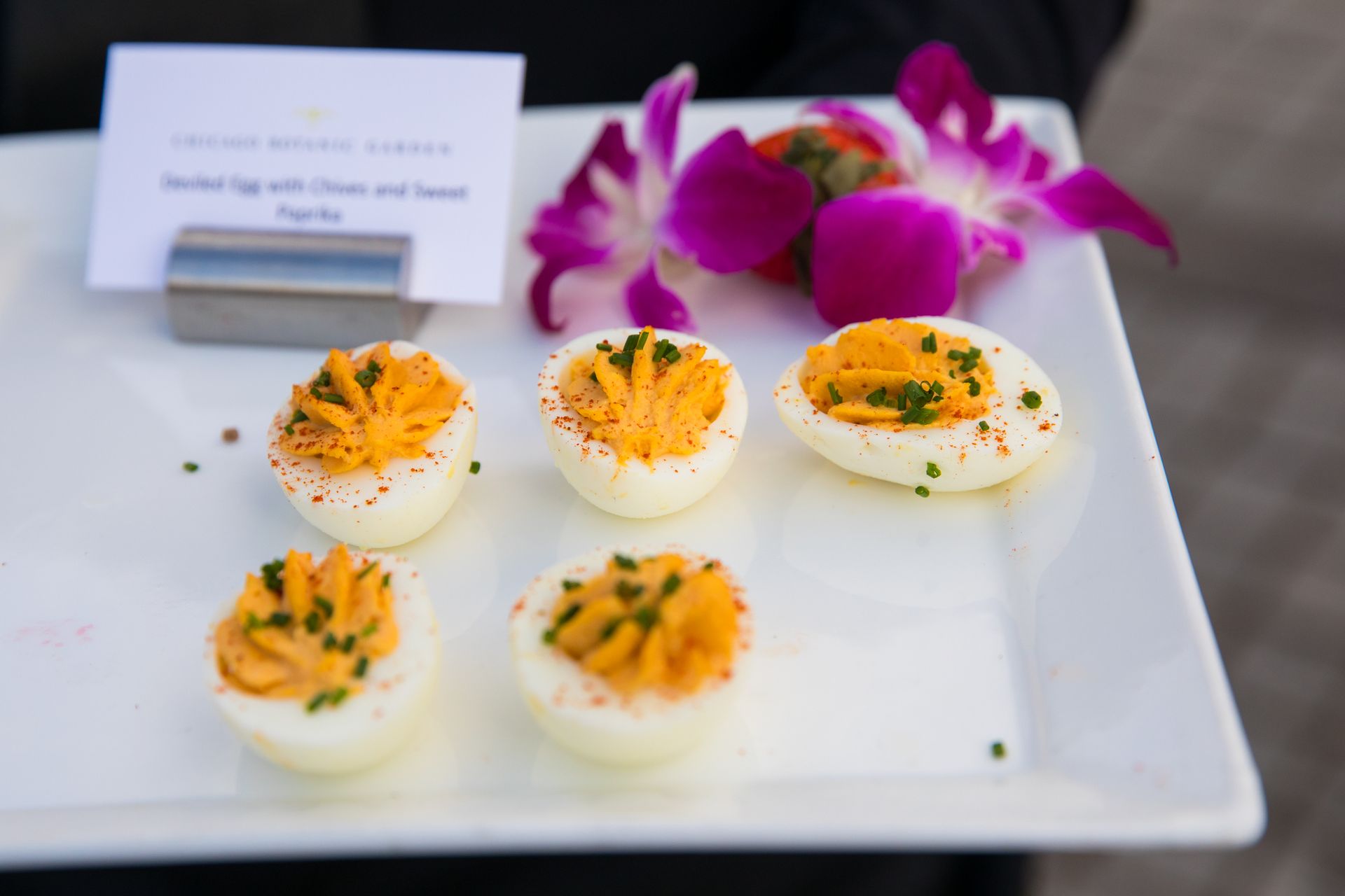 A white plate topped with hard boiled eggs and flowers.