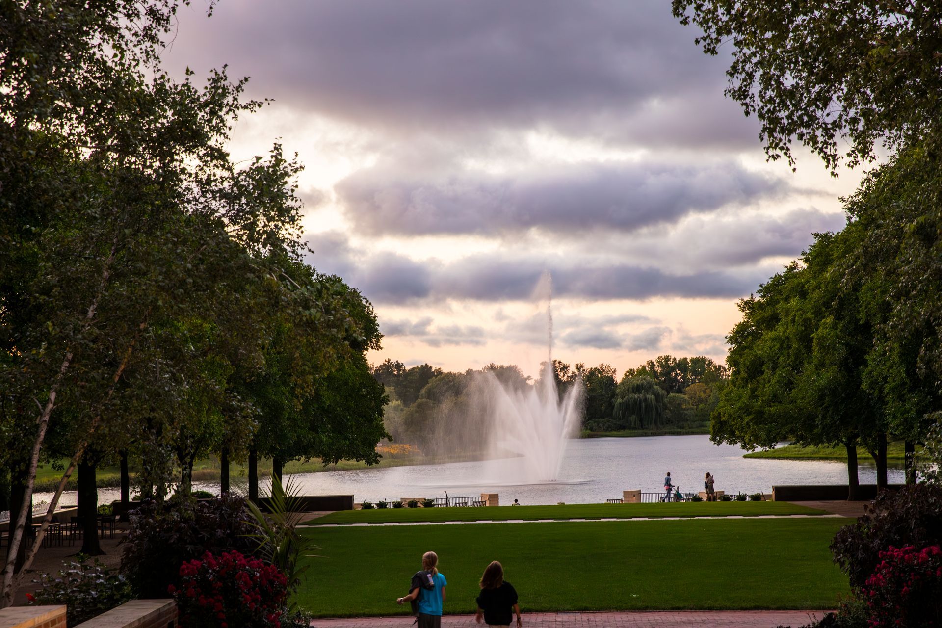 A couple of people standing in front of a fountain in a park