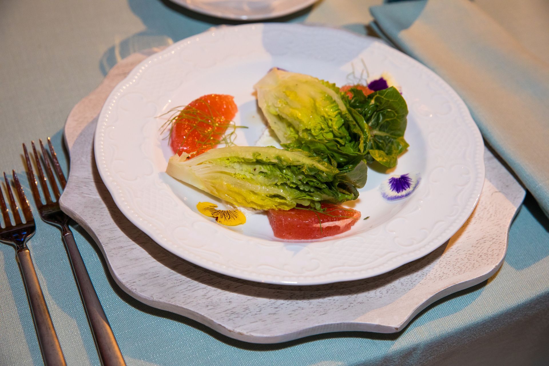A white plate topped with a salad and a fork on a table.