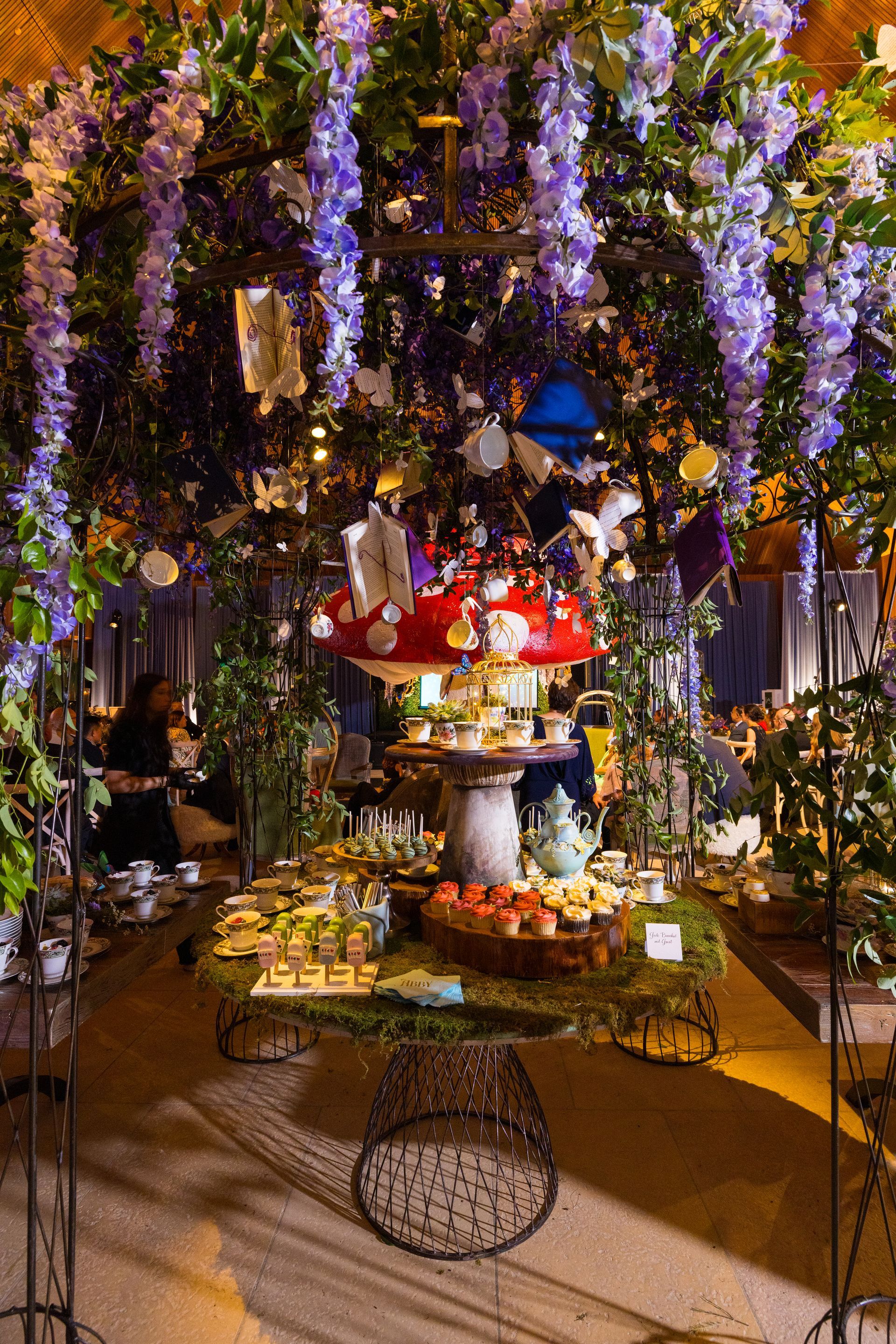 A table with a mushroom on top of it and flowers hanging from the ceiling.