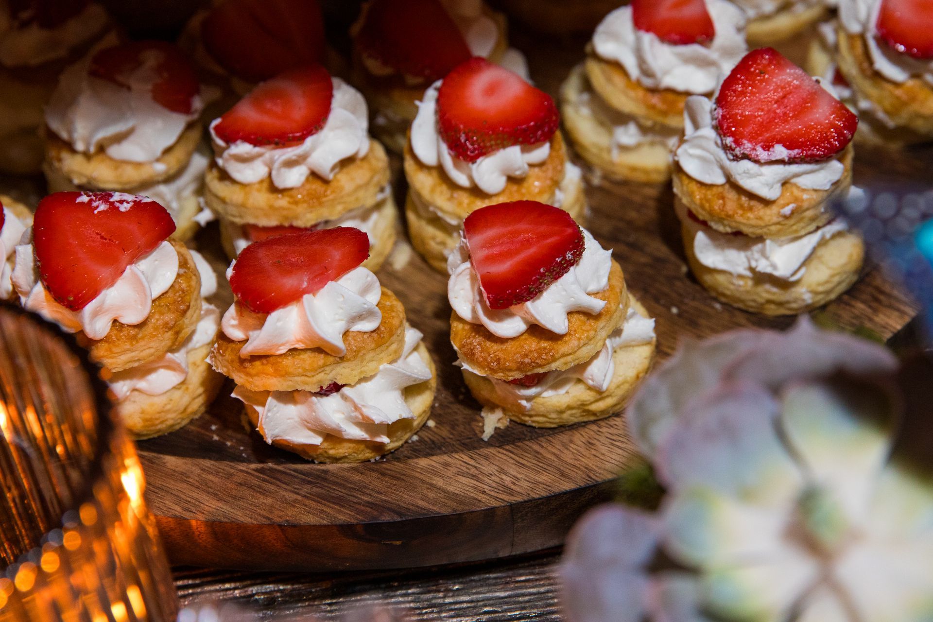 A wooden cutting board topped with strawberries and whipped cream.
