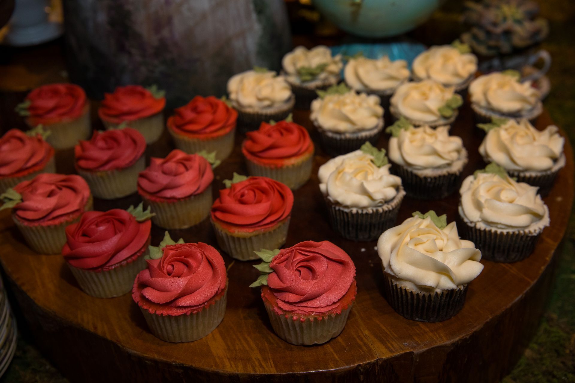 A wooden table topped with cupcakes decorated with red and white frosting.