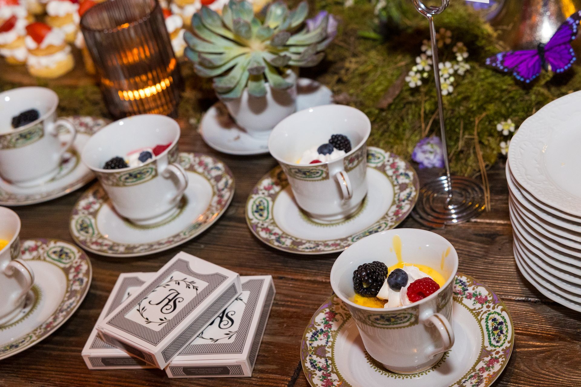 A table topped with cups and saucers filled with fruit and playing cards.