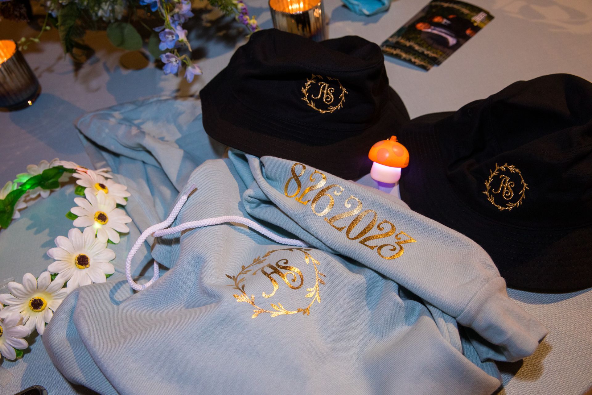 A table with a bunch of hats and hoodies on it