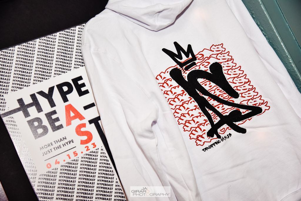 A white hoodie with a crown on it is sitting next to a book titled hype beast.