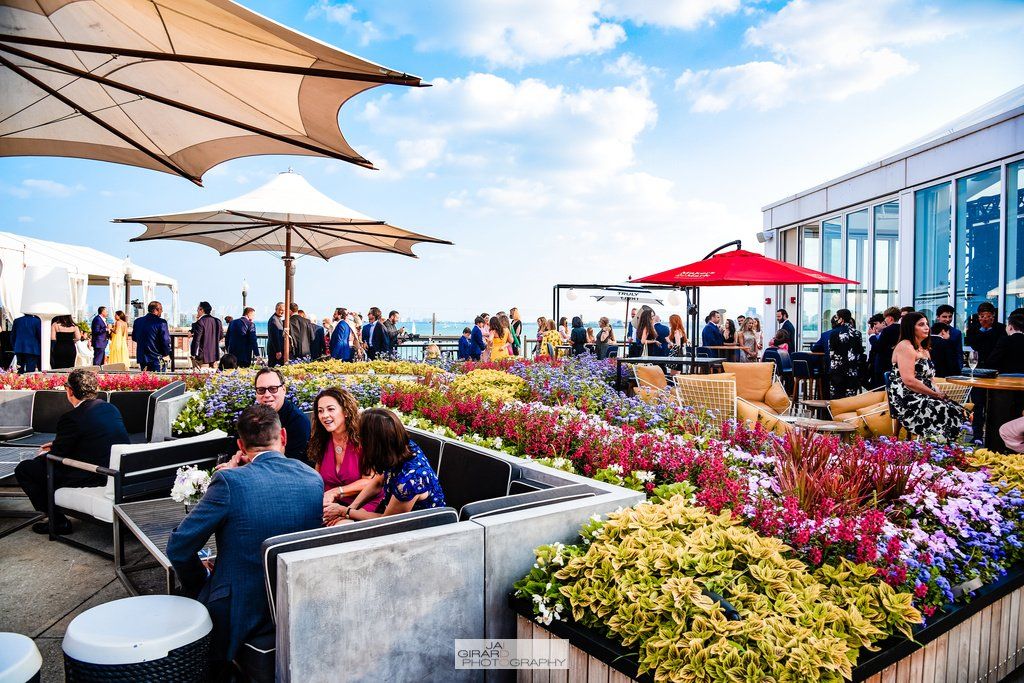 A group of people are sitting at tables under umbrellas on a patio.