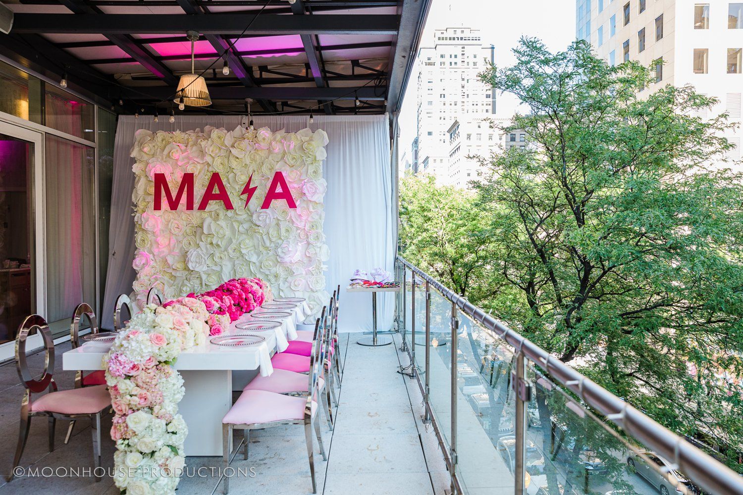A balcony with a table and chairs and a wall of flowers.