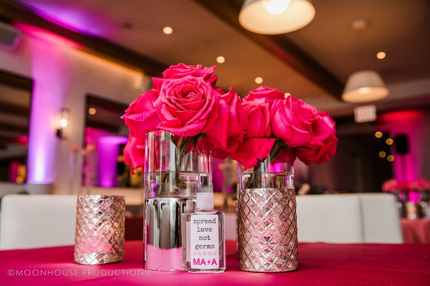 A vase filled with pink roses sits on a table.