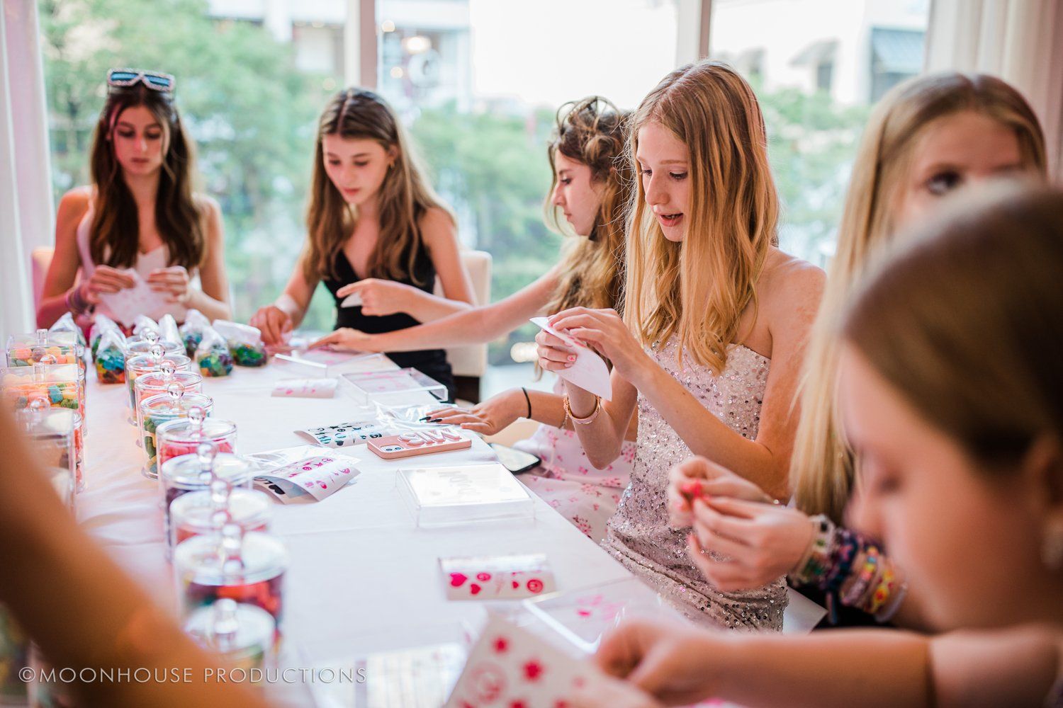 A group of young girls are sitting at a table making crafts.