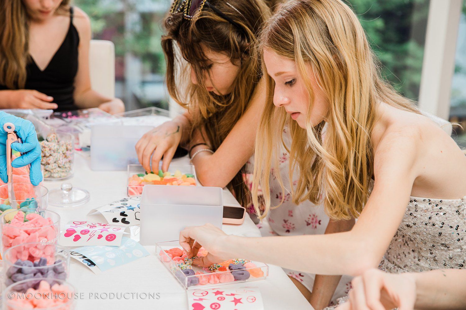 A group of young girls are sitting at a table making crafts.