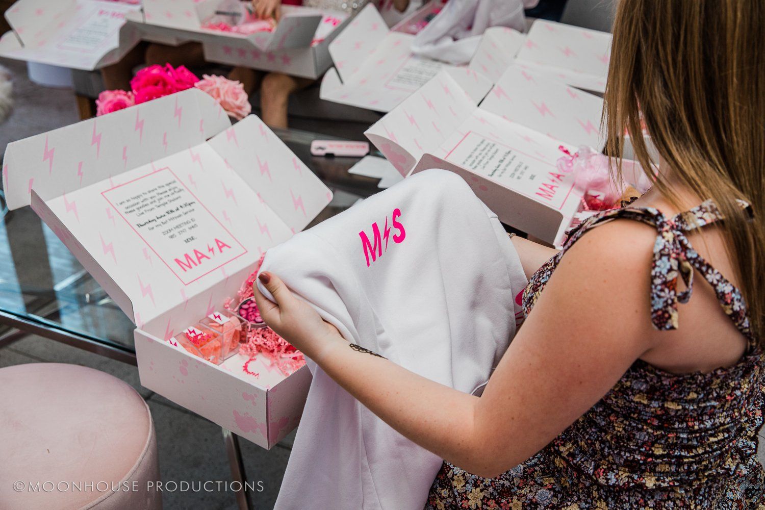 A woman is holding a white shirt with the letters ms embroidered on it.