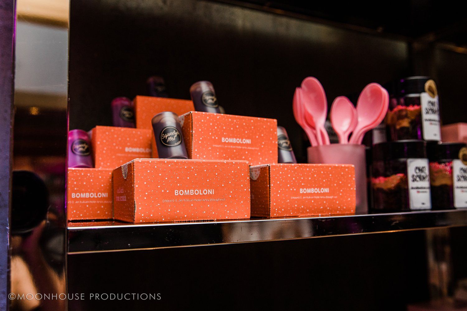 A shelf with boxes and pink spoons on it