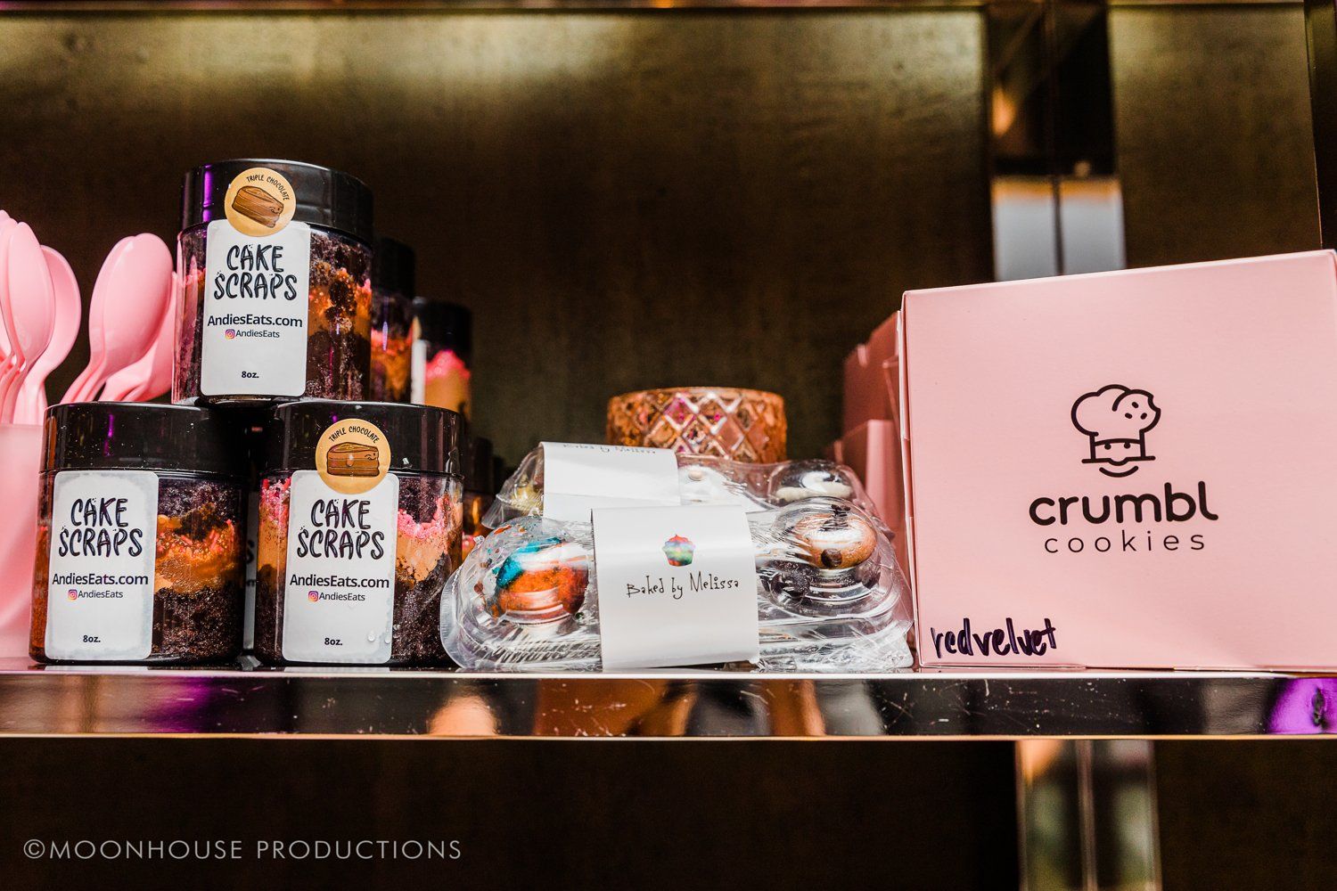 A shelf filled with jars of food and a box of crumbl cookies.