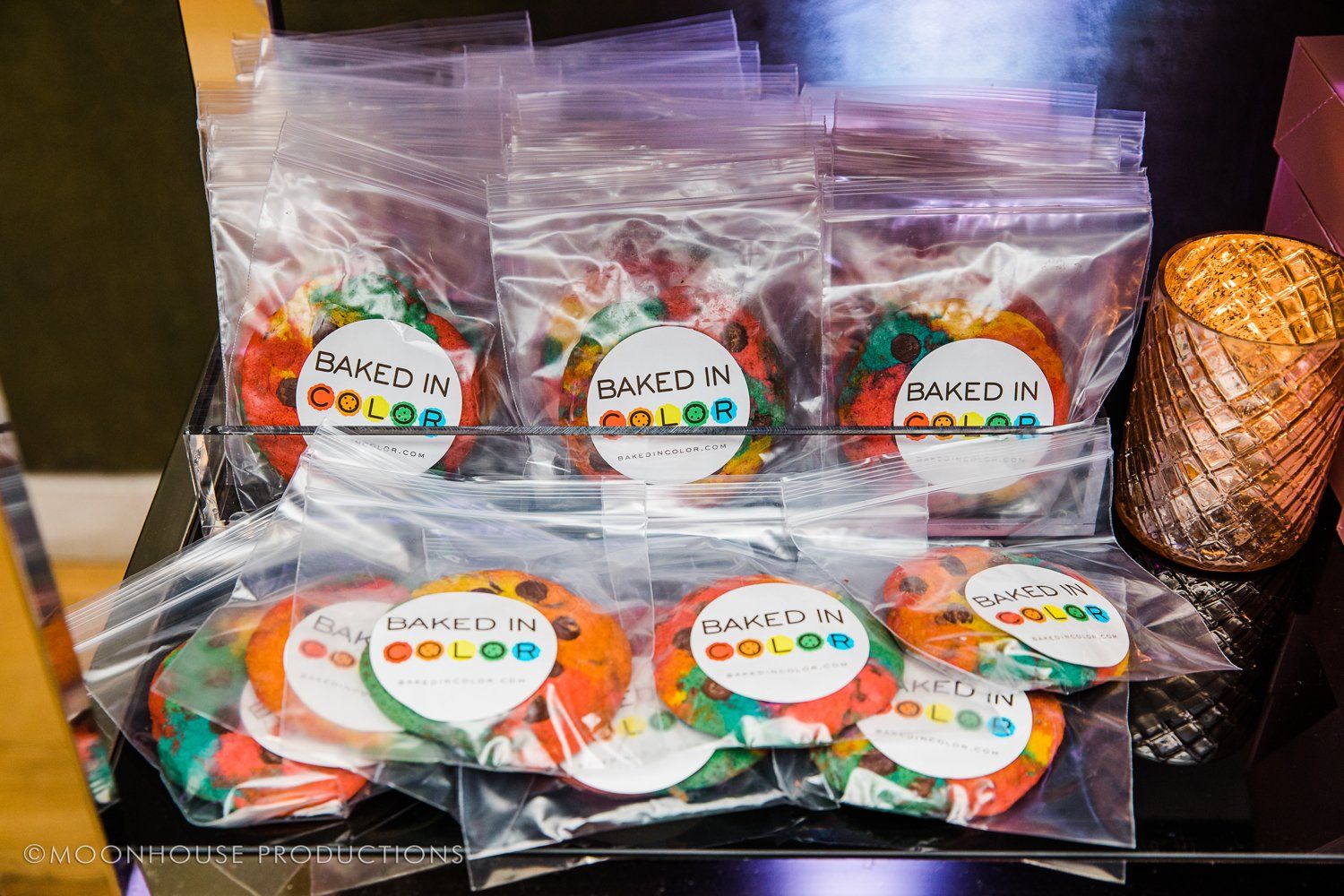 A bunch of bags of baked in color cookies are sitting on a table.