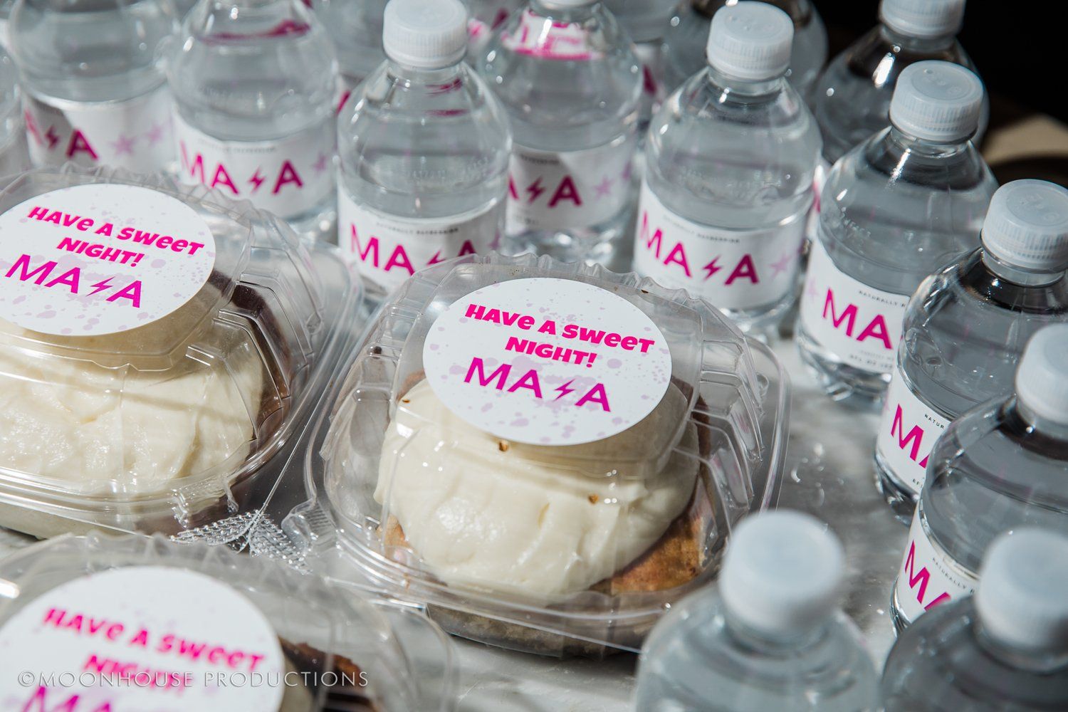 A table topped with water bottles and cupcakes.