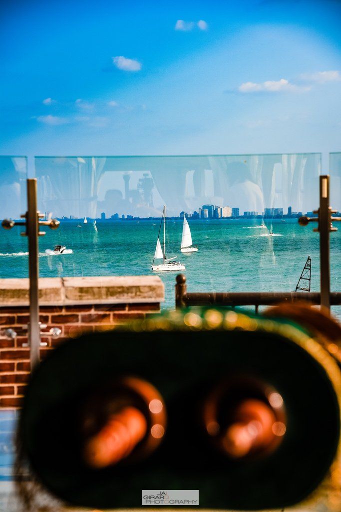 A person is looking through binoculars at boats in the water.