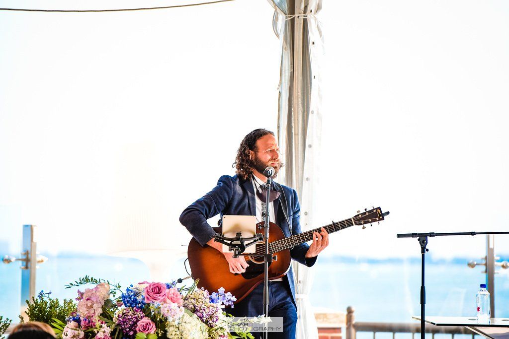 A man is playing a guitar and singing into a microphone at a wedding.