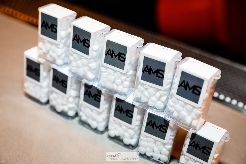 A bunch of containers of ams candy are stacked on top of each other on a table.