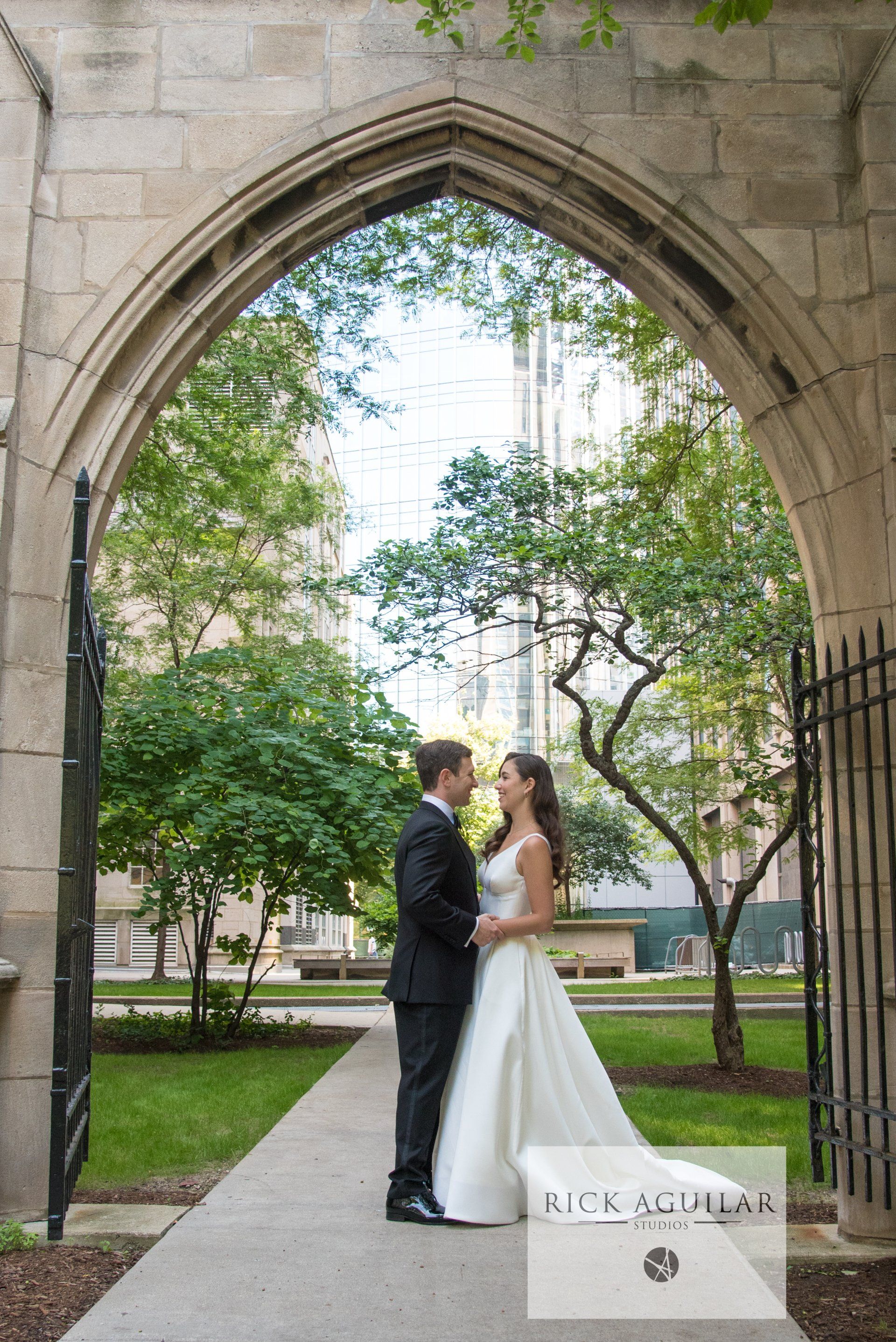 A bride and groom are posing for a picture in front of a stone archway.